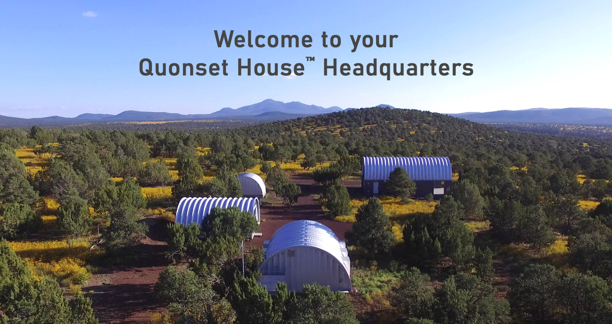 Image of a landscape mountains in the distance and Quonset huts in the foreground, and the words, "Welcome to your Quonset House headquarters."